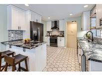 Bright kitchen features white cabinets, black stainless appliances, and black and white patterned tile floors at 4844 Vallejo St, Denver, CO 80221