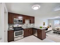 Modern kitchen featuring stainless steel appliances, granite countertops, and stylish backsplash, open to living area at 4812 W 8Th Ave, Denver, CO 80204