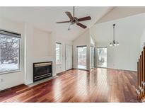 Bright living room with a fireplace, ceiling fan, vaulted ceiling and hardwood floors at 2121 S Troy Way, Aurora, CO 80014