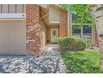 Charming front entrance with brick accents, mature landscaping, and inviting pathway to the front door at 8164 Flower Cir, Arvada, CO 80005
