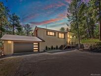 Charming home exterior features a modern garage door, neutral paint, and a wooded lot at 8422 S Ault Ln, Morrison, CO 80465
