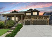 Charming two-story home with a stone facade, covered porch, and an attached three-car garage at 6186 S Millbrook Way, Aurora, CO 80016