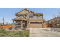 Charming two-story home featuring a well-manicured lawn and a welcoming front porch with stone supports at 9574 Keystone Trl, Parker, CO 80134