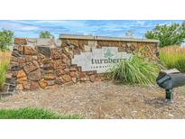 Stone entrance sign to Turnberry community with landscaping, and sunny sky at 13458 E 111Th Ave, Commerce City, CO 80022