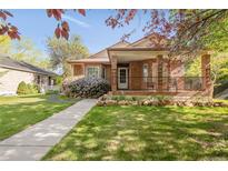 Charming brick home featuring a covered front porch with lovely landscaping and healthy green lawn at 306 E Iowa Ave, Berthoud, CO 80513