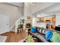 Cozy living room featuring a fireplace, comfortable seating, and an open view to the kitchen at 8371 S Upham Way # 208, Littleton, CO 80128