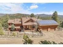 Stunning exterior showcasing a log cabin-style home with solar panels and mountain views at 33121 Lynx Ln, Evergreen, CO 80439