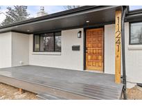 Inviting front porch featuring painted brick, a new wood deck, and a stylish front door at 11241 W 60Th Ave, Arvada, CO 80004