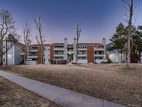 Exterior of a multi-story condo complex with brick accents, gray siding, and well-kept lawn at sunset at 14495 E 1St Dr # C2, Aurora, CO 80011