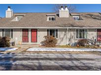 Charming townhouse featuring a red door, dormer windows, and neutral siding, creating a welcoming curb appeal at 1244 S Reed St # 2, Lakewood, CO 80232