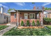 Charming brick home featuring a well-manicured lawn, tidy front yard with flowerbed, and a covered front porch entrance at 1939 S Sherman St, Denver, CO 80210