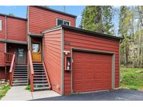 Red exterior showcasing a garage and stairway leading to the front door at 876 Broken Lance Dr, Breckenridge, CO 80424