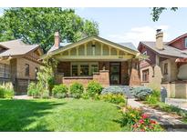 Charming brick home with a well-manicured lawn, beautiful landscaping, and a welcoming front porch at 843 Adams St, Denver, CO 80206