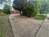 Long concrete driveway leading up to a well-maintained brick home with mature trees at 387 Tucson St, Aurora, CO 80011