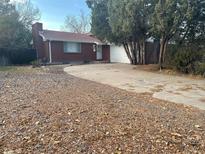 Brick ranch house with attached garage and driveway, surrounded by trees and landscaping at 387 Tucson St, Aurora, CO 80011