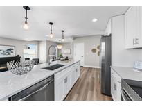 Bright, modern kitchen featuring an island with sink, white cabinets, and stainless steel appliances at 2140 S Ash St # 101, Denver, CO 80222