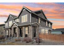 Beautiful gray two-story home featuring stone accents, gabled roof, and professionally landscaped front yard at 21411 E 60Th Ave, Aurora, CO 80019