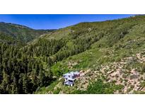 Stunning view of the house nestled in the mountains and surrounded by lush greenery at 2602 Hidden Valley Road, Sedalia, CO 80135