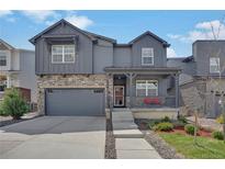 Charming two-story home with stone accents, a covered porch, a gray exterior, and a well-manicured lawn at 9836 Banner Peak St, Littleton, CO 80125