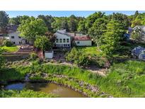 Expansive backyard with mature trees and lush landscaping, creating a private oasis near a creek at 9465 W 77Th Dr, Arvada, CO 80005
