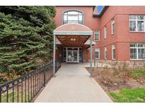 Inviting entrance with covered walkway, mature trees, and brick exterior at 300 Hudson at 300 Hudson St # 109, Denver, CO 80220