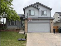 Charming gray two-story home with a basketball hoop and attached two car garage, and landscaped front yard at 12119 Forest St, Thornton, CO 80241