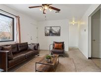 Cozy living room featuring a leather sofa, wood coffee table, and whitewashed brick accent wall at 7600 Monaco St, Commerce City, CO 80022