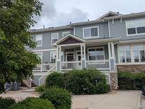 Two story home features a covered porch, green foliage and a partial stone facade at 9578 Pearl Cir # 105, Parker, CO 80134