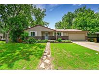 Charming ranch home featuring a well-manicured lawn and beautiful front yard landscaping with stone walkway at 10224 W 68Th Way, Arvada, CO 80004