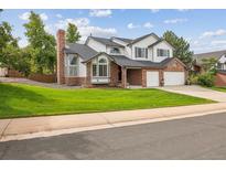 Charming two-story home with manicured lawn, brick accents, and two-car garage under a cloudy blue sky at 2378 Wynterbrook Dr, Highlands Ranch, CO 80126