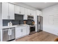 Modern kitchen featuring white cabinetry, stainless steel appliances, and sleek countertops at 2466 S Delaware St # 3, Denver, CO 80223