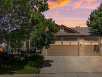 Charming home exterior featuring a three car garage and beautiful landscaping at sunset at 885 Sage Sparrow Cir, Highlands Ranch, CO 80129