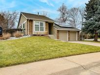 Charming brick home featuring a well-manicured lawn, two-car garage, and energy-efficient solar panels at 8217 S Syracuse Ct, Centennial, CO 80112