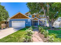 Charming two-story home with blue siding, a landscaped yard, and a welcoming front porch at 930 Kearney St, Denver, CO 80220