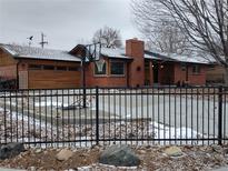 Charming brick home with a basketball hoop, updated wooden garage door and a manicured front yard with a fence at 2700 S High St, Denver, CO 80210