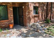 Inviting front entrance with red brick facade, screen door, and rock accents around the exterior of the home at 2261 S Buckley Rd # 102, Aurora, CO 80013