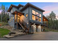 Stunning contemporary home boasts an attached two-car garage and inviting stairway to the covered porch at 6803 Snowshoe Trl, Evergreen, CO 80439