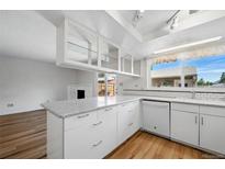 Bright kitchen with wood floors, white cabinets, and an island with light countertop at 10311 E Evans Ave # 133, Aurora, CO 80247