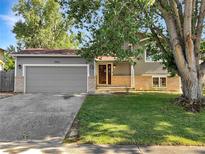Charming home featuring a gray garage door, brick accents, and a well-maintained front yard at 542 Hawthorn Cir, Frederick, CO 80530