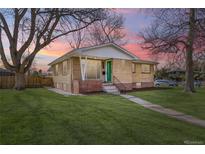 Charming brick home featuring a well-manicured lawn, mature trees, and colorful sky at 5971 S Crestview St, Littleton, CO 80120