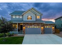 Inviting two-story home with a stone facade and well-manicured lawn, bathed in the warm glow of twilight at 1315 Sidewinder Cir, Castle Rock, CO 80108