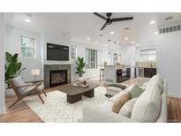 Bright living room featuring a fireplace, hardwood floors, and an open layout connecting to the kitchen at 3322 W 26Th Ave, Denver, CO 80211