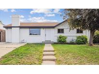 Charming brick home features a well-manicured lawn and welcoming walkway to the front door at 7952 Zuni St, Denver, CO 80221