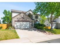 Charming two-story home featuring a stone facade, lush lawn, and an attached two-car garage at 19817 E Prentice Ave, Centennial, CO 80015