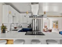 Modern kitchen featuring white cabinets, stainless steel appliances, and a large island with seating at 46 S Perry St, Denver, CO 80219