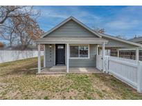 Charming single-story home featuring a covered front porch and classic architectural details with a white picket fence at 6660 Locust St, Commerce City, CO 80022