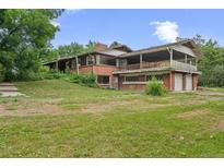 Spacious brick home featuring a charming covered balcony and a lush green lawn at 7350 Field St, Arvada, CO 80005