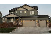 Two-story house with stone accents and a three-car garage at 16812 Buffalo Run Dr, Commerce City, CO 80022