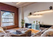 Inviting living room featuring exposed brick, large window, and modern shelving decor at 1555 California St # 605, Denver, CO 80202