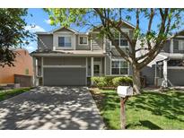 Charming two-story home with a gray exterior, two-car garage, and well-maintained front yard at 9690 Lansing Cir, Commerce City, CO 80022